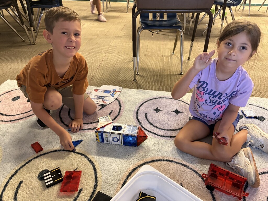 A boy and girl are building things with magnetic tiles.