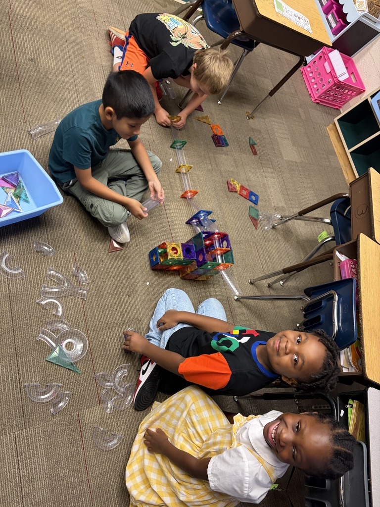 Four students build with magnetic tiles.