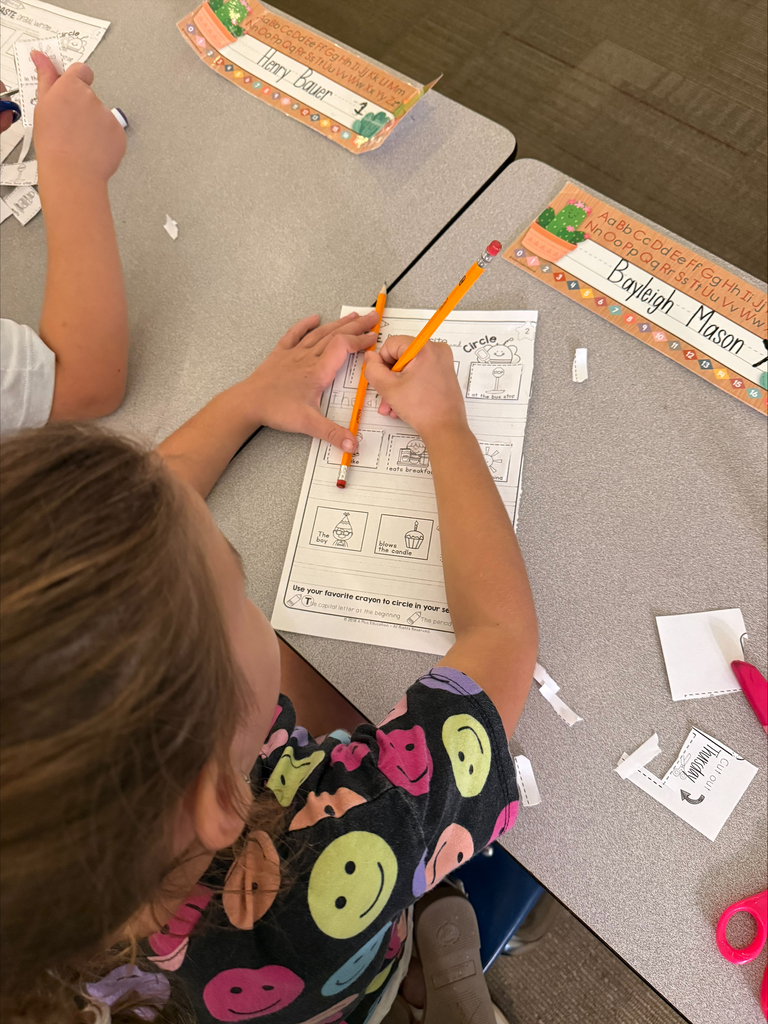 A student is seated at a desk practicing writing.