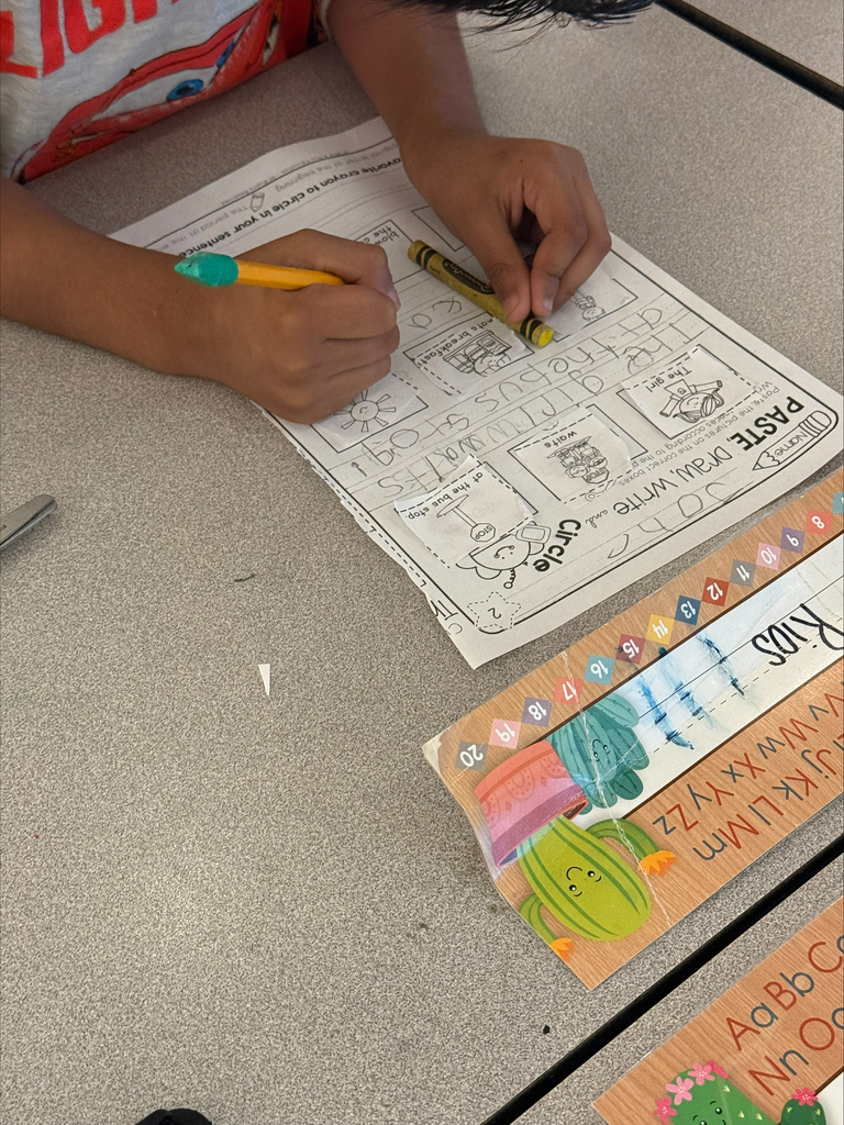 A student is using a crayon to practice spacing of words.