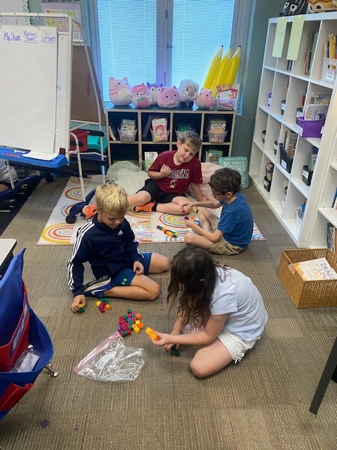 Four children are using blocks to practice math skills.