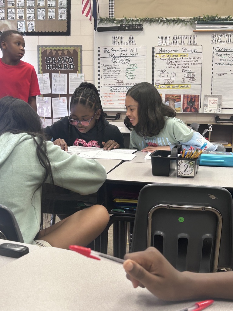 Students sitting at their desks talk about their writing.