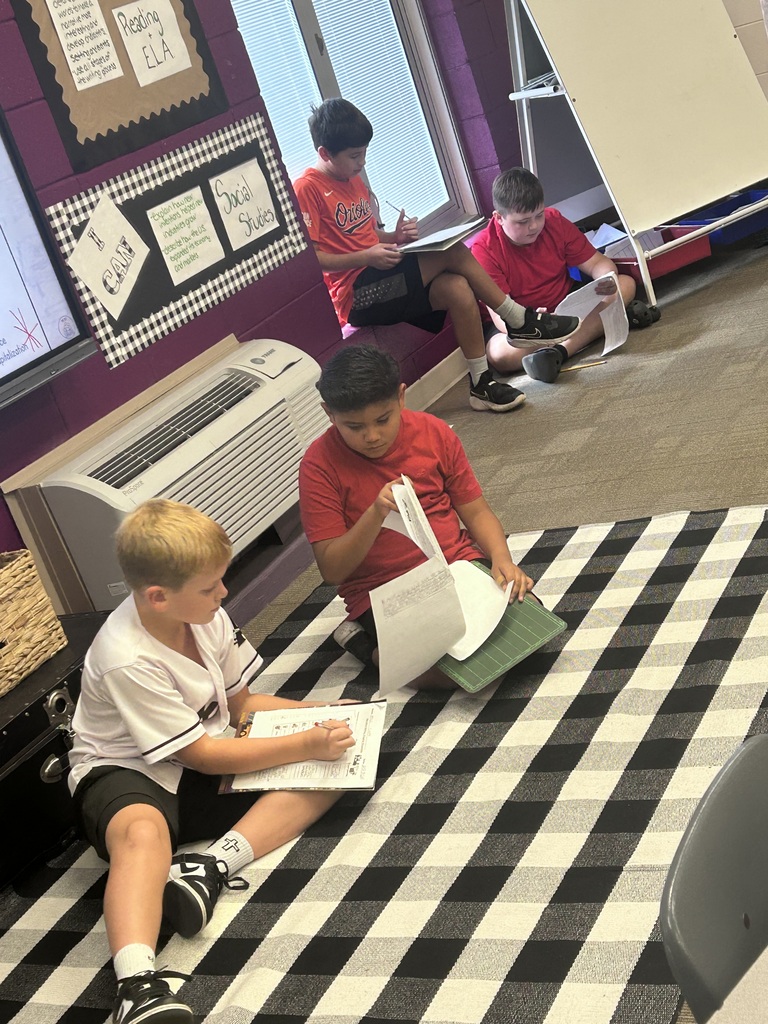 Four boys sit together to read and discuss their writing.