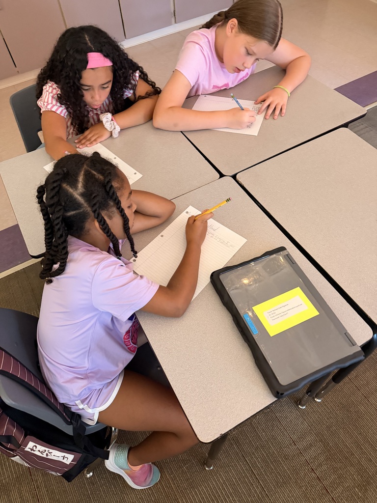 Three students are writing at their desks.