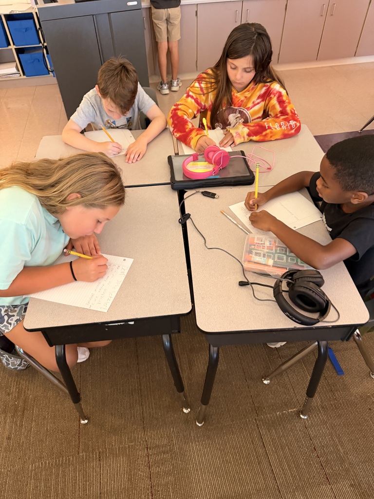 Four students are writing at their desks.