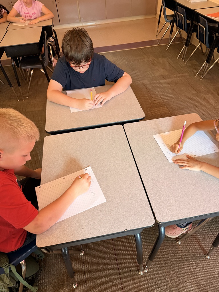 Three students are writing at their desks.