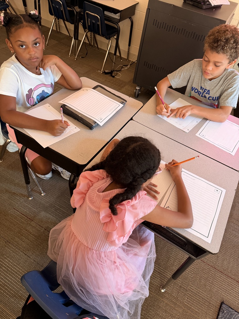 Three students are writing at their desks.