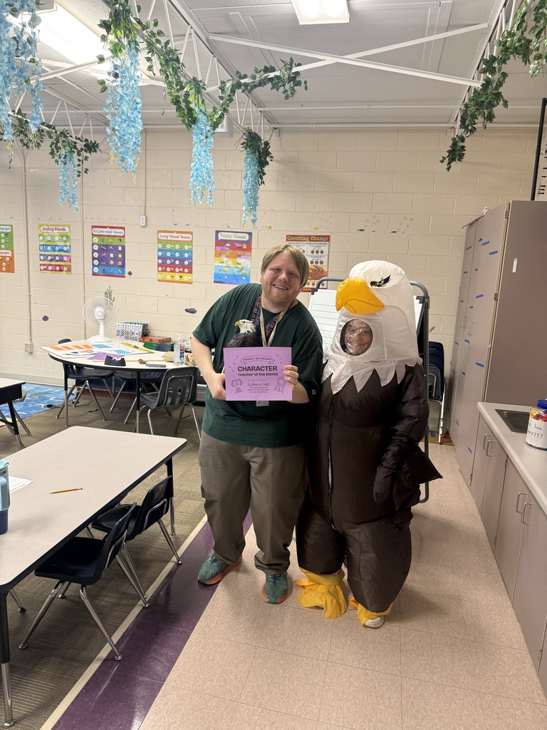A teacher holds a certificate while standing next to someone in an eagle costume.