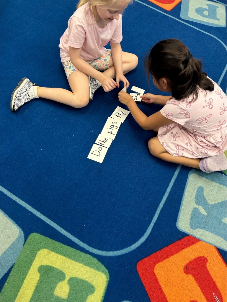 Two girls are placing word flash cards into sentence order.