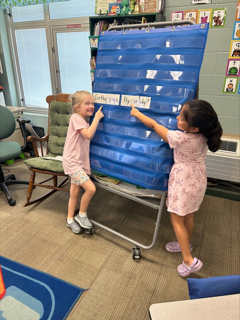 Two students are placing word flash cards into a pocket chart in sentence order.