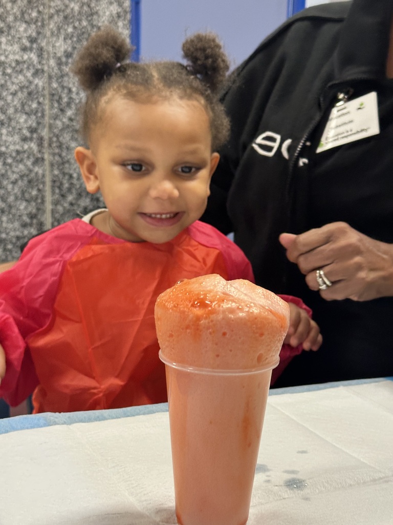 A girl with an excited expression watches foam rising from a cup.