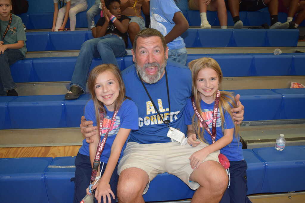 Coach and students in blue shirts pose on a bleacher at a Incentive event.