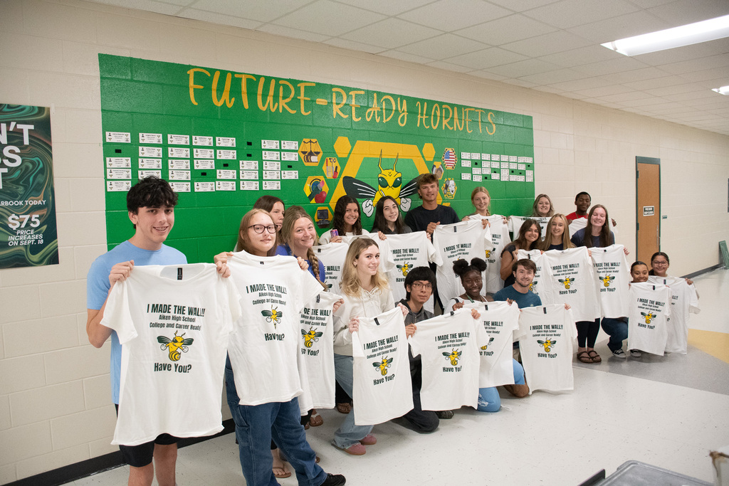A group of students standing in front of a green wall.