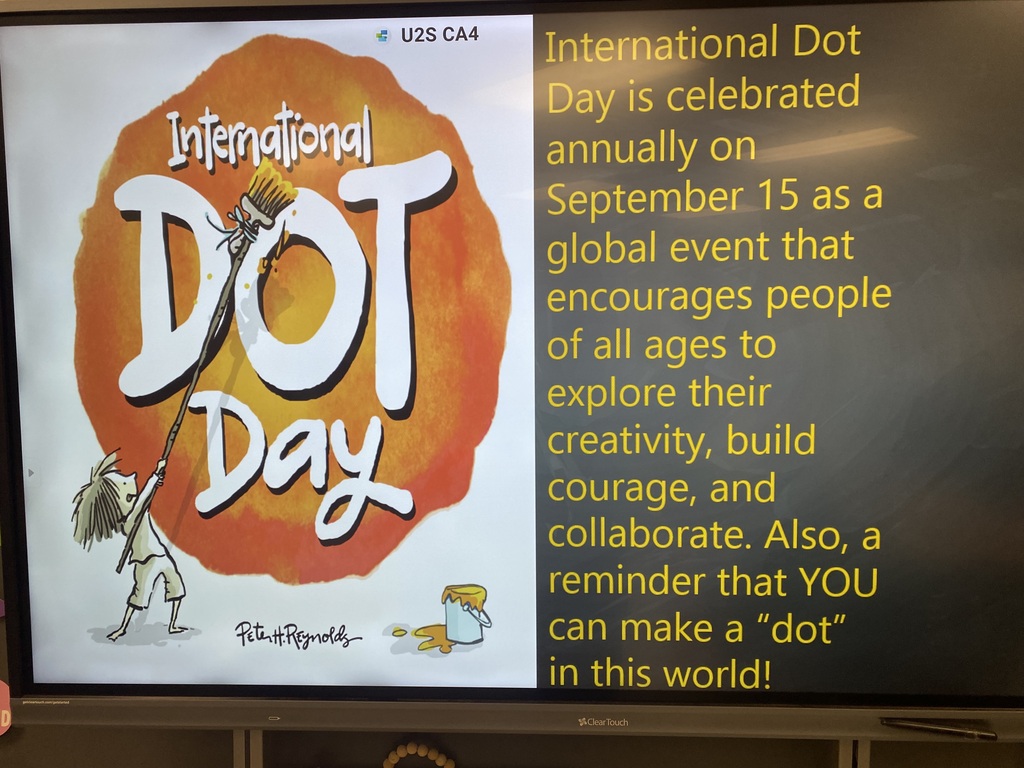 Monitor displays the text "International Dot Day" with an illustration of a figure holding a paintbrush and text about creativity and collaboration.