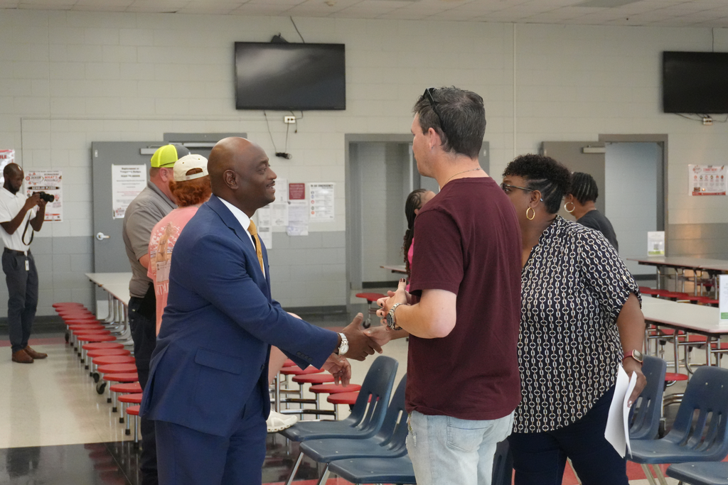 Superintendent shaking hands with community member.