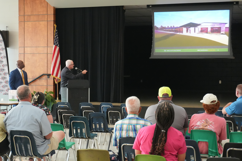 Community members listening to presentation in cefeteria.