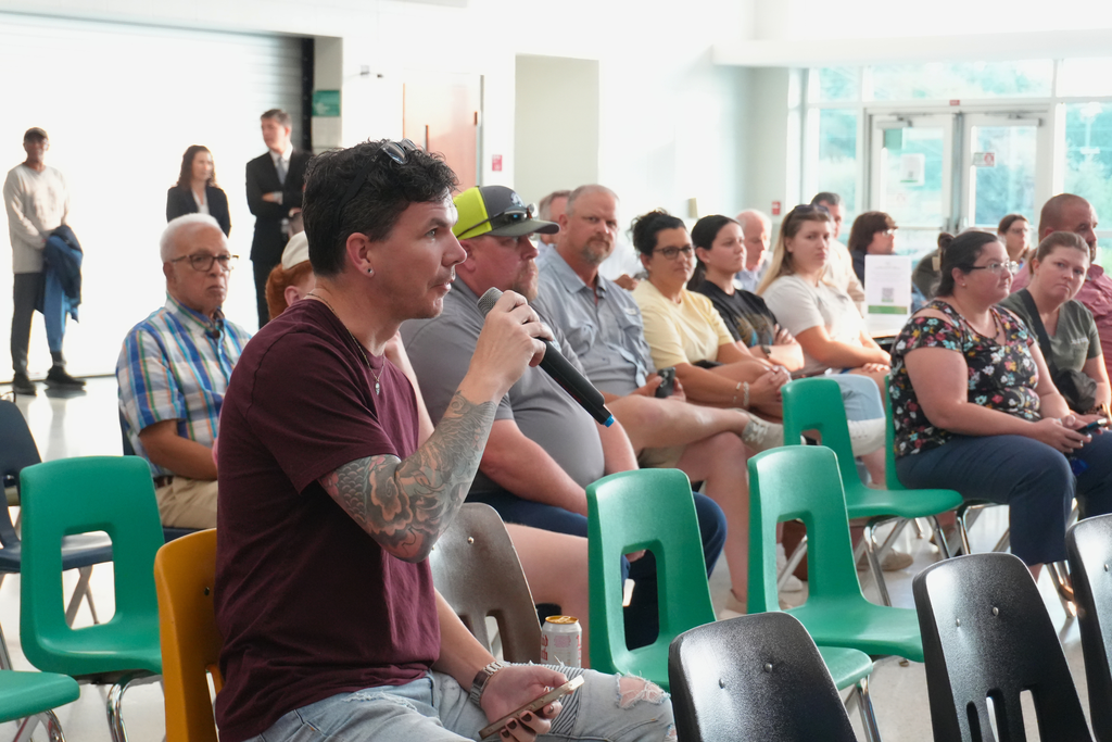 Community member holding microphone and speaking at meeting.