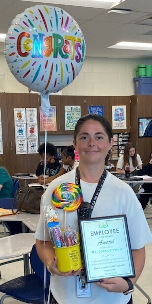 Ms. Priest holding an employee of the month award.