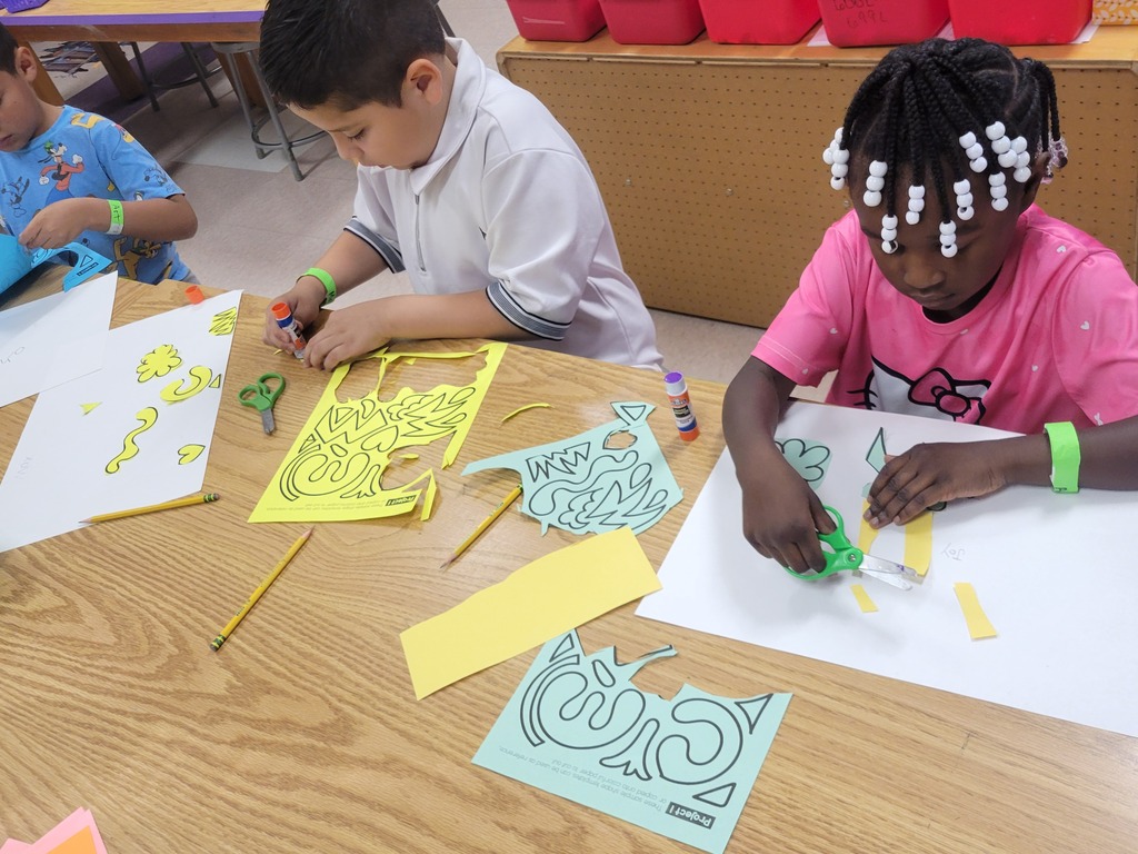 Two students are cutting and pasting an art craft.