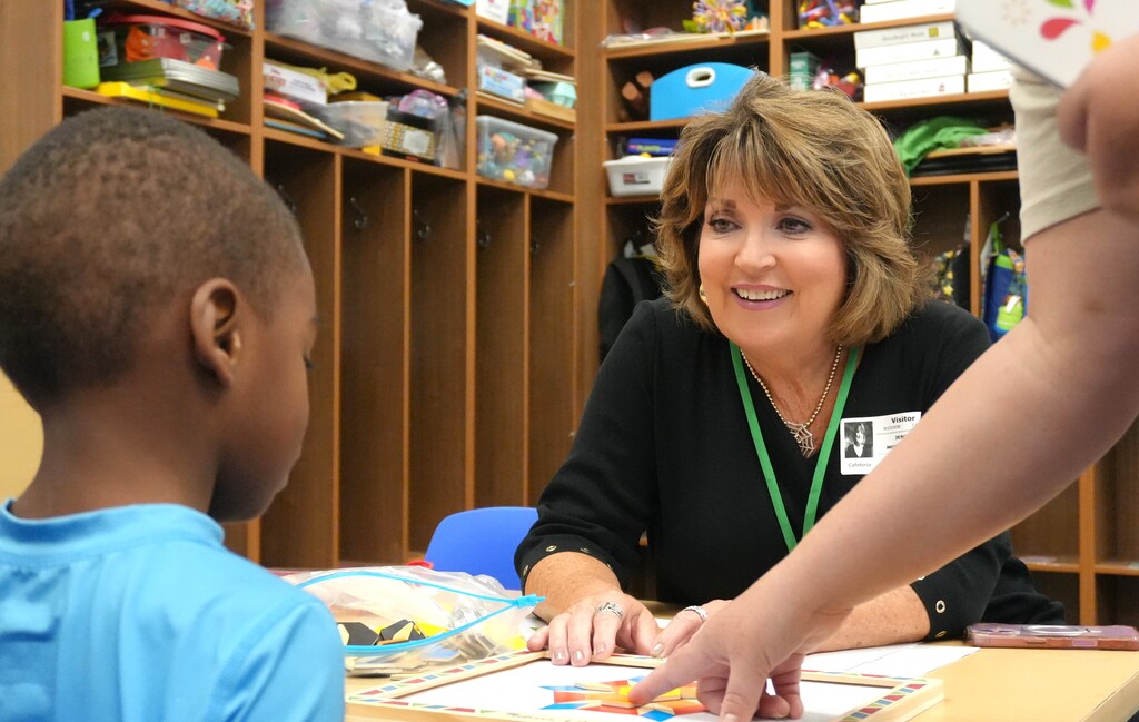 Woman in a black top seated with a child. Child wears blue shirt. They are interacting.