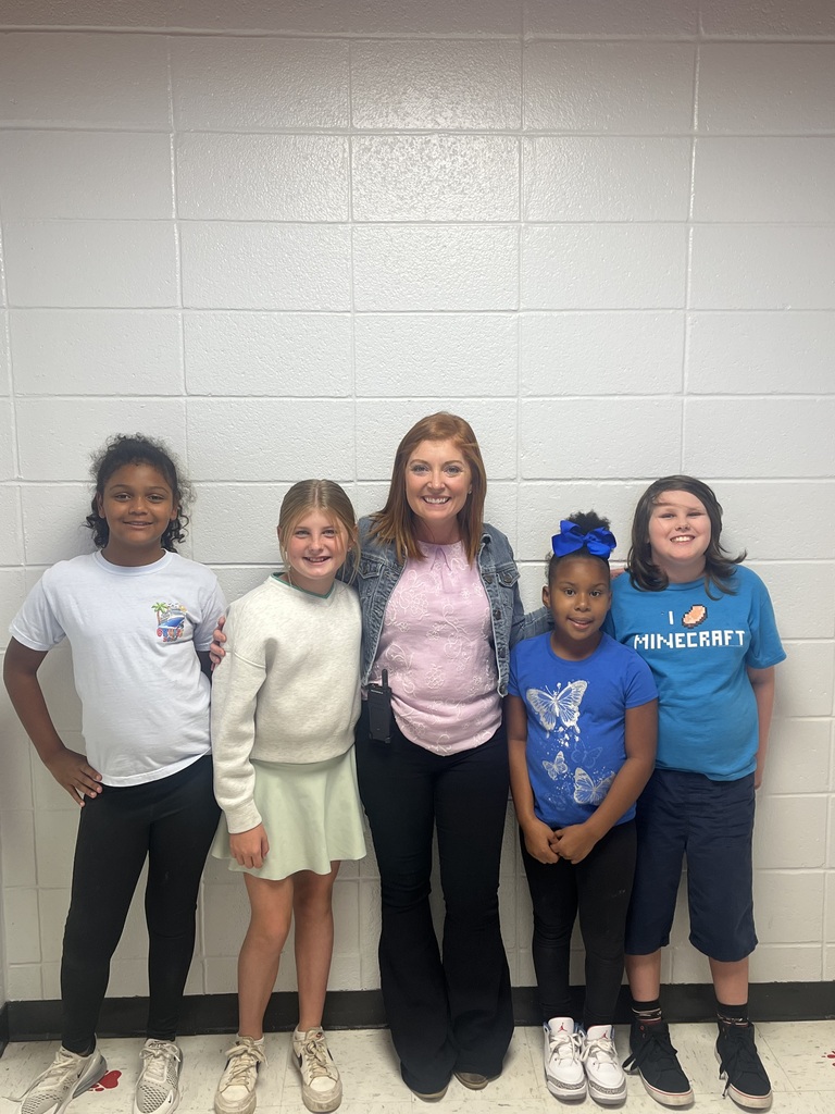A woman and four children, all wearing sneakers, smile for a group photo against a white wall.