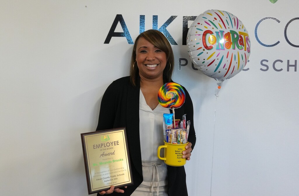 Ms. Miranda Brooks holding an employee of the month award.