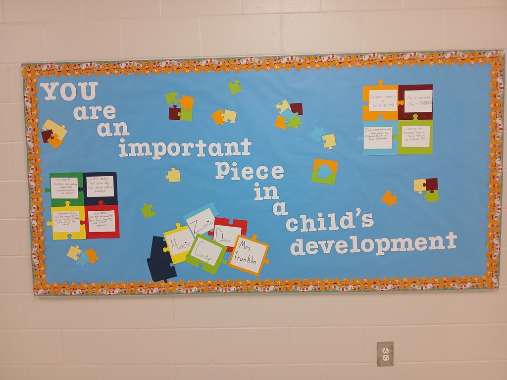 Blue bulletin board with the words "You are an important piece in a child's development" and some multicolored blocks and arrows scattered around. 