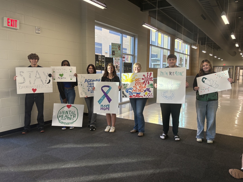 Group of students standing in a school hallway with signs on mental health awareness. 