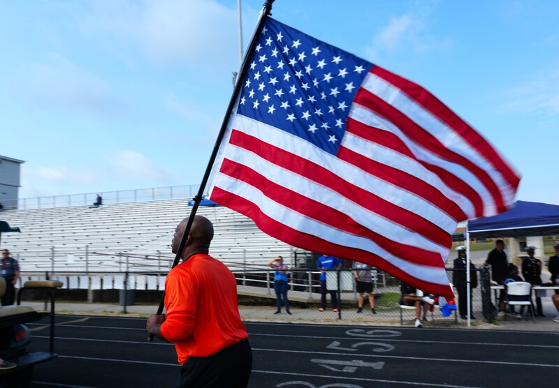 Dr. Corey Murphy runs holding an American flag.