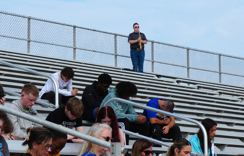 A trumpet player stands in the bleachers to play Taps.