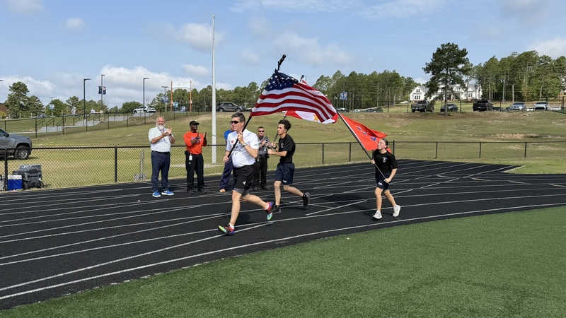 Assistant Superintendent of High Schools running with a US flag.