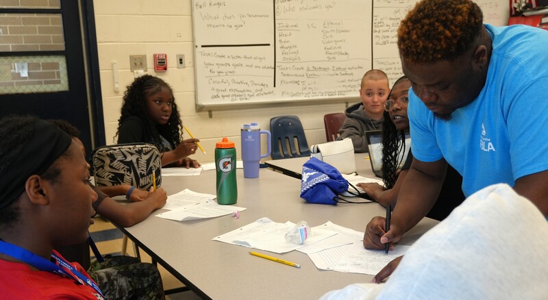 A teacher works one on one with a student on financial literacy.