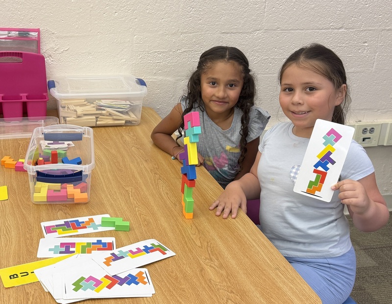 Two girls show off the tower of blocks they created.