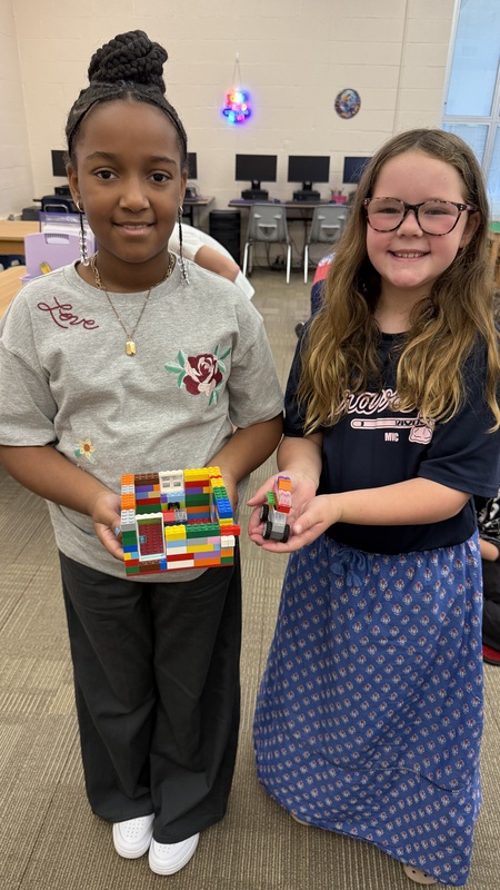 Two smiling girls show off their Lego creations.