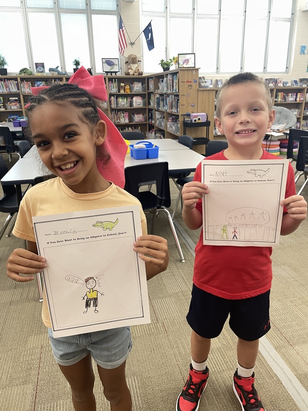 A smiling boy and girl show the work they completed.