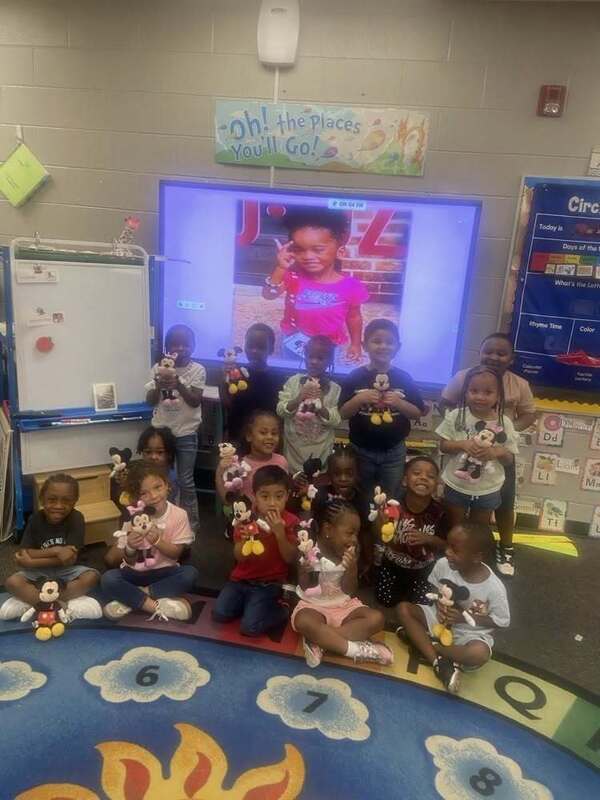 Students posing with their stuffed animals in front of an image of Javeayah Harris.
