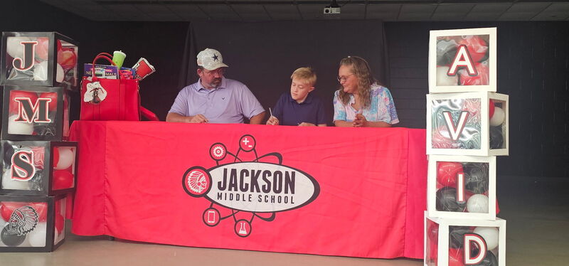 Scholar with parents signing AVID commitment.