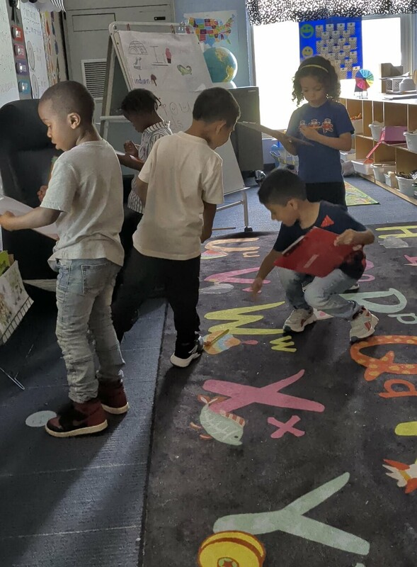 Several students are walking around the classroom for a scavenger hunt.