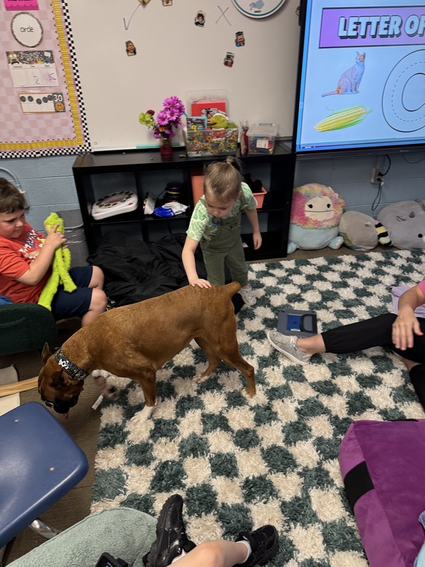 Two students stand next to Ruby the therapy dog.
