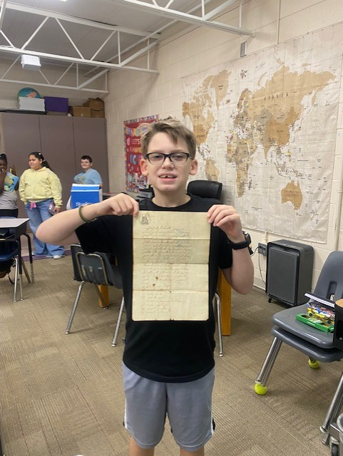A male student holds up a paper of classwork.