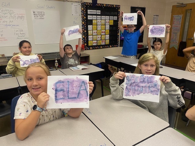 A class of students hold up their sheets of paper to show their hidden messages.