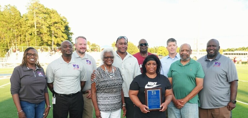 District leaders, family of J.O. Brown smile with plaque.