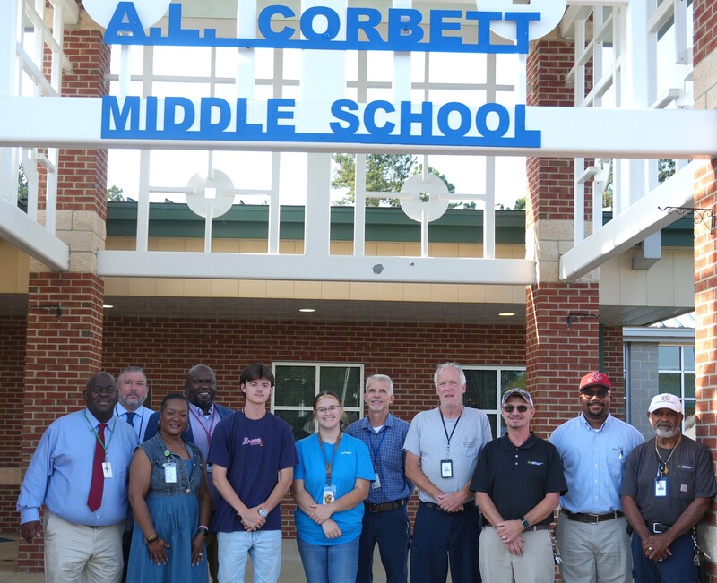 District and school leaders as well as Wagener-Salley pose under sign.