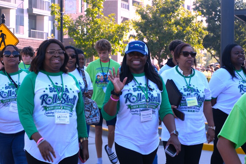 Participants wave at camera during Roll and Stroll walk.
