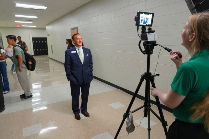 Board member smiling while communication team sets up camera.