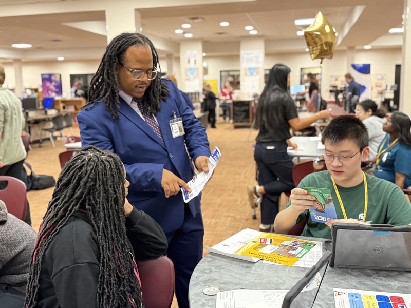College Representative talks with two high school students.