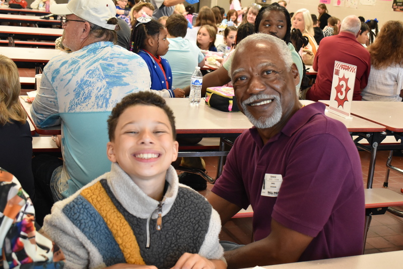 Grandparents and families at lunch with students.