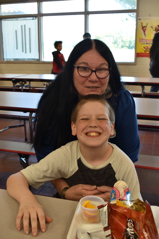 Grandparents and families at lunch with students.
