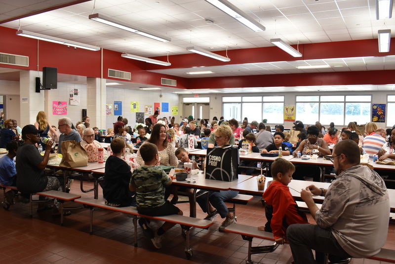 Grandparents and families at lunch with students.