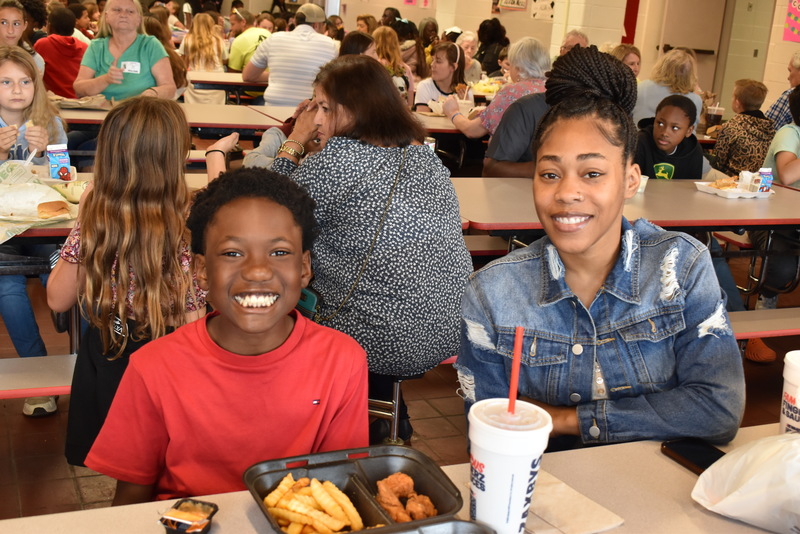 Grandparents and families at lunch with students.